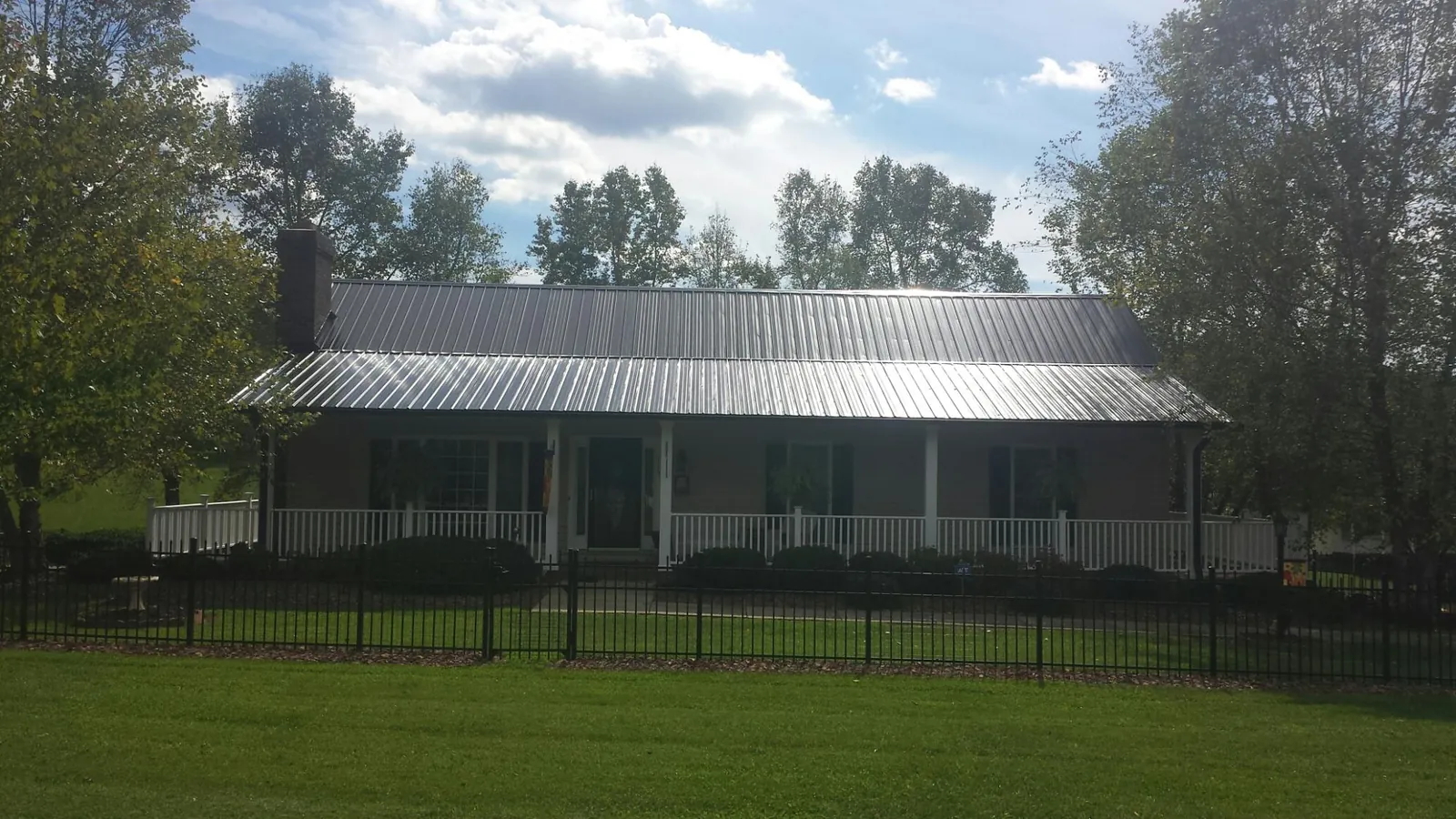 Gray metal roof on a brick ranch with a full width front porch — Gutter Guard Installation work by our crew in Jeddo